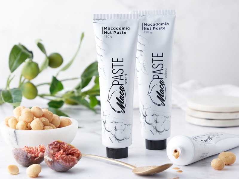 Macadamia Nut Paste tubes styled with fresh figs, macadamias and a brass spoon.